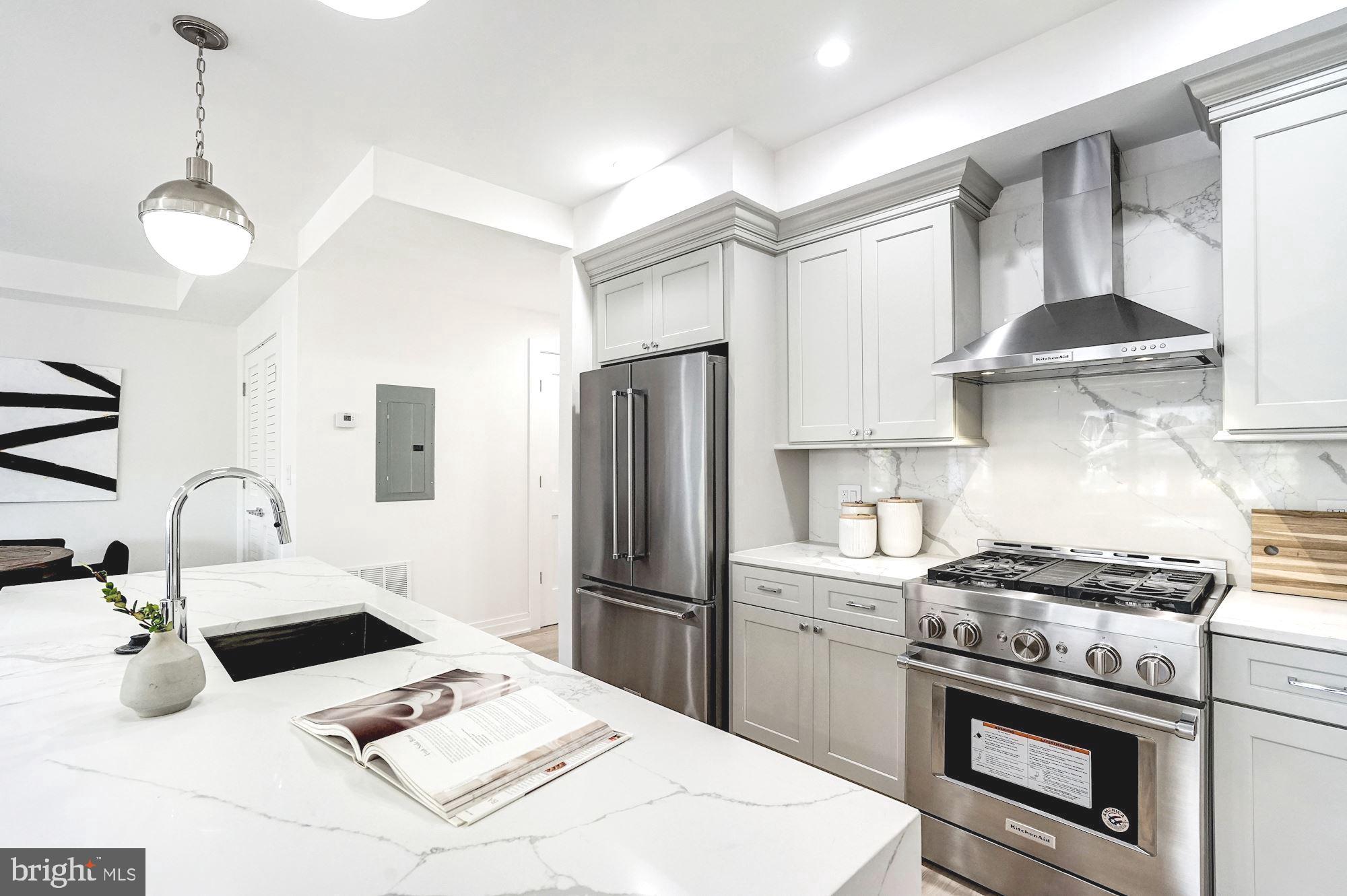 1603 Isherwood Street Northeast, Unit 2 Washington, DC 20002 - Photo 13 of 24 a kitchen with kitchen island a stove a refrigerator and a sink with wooden floor