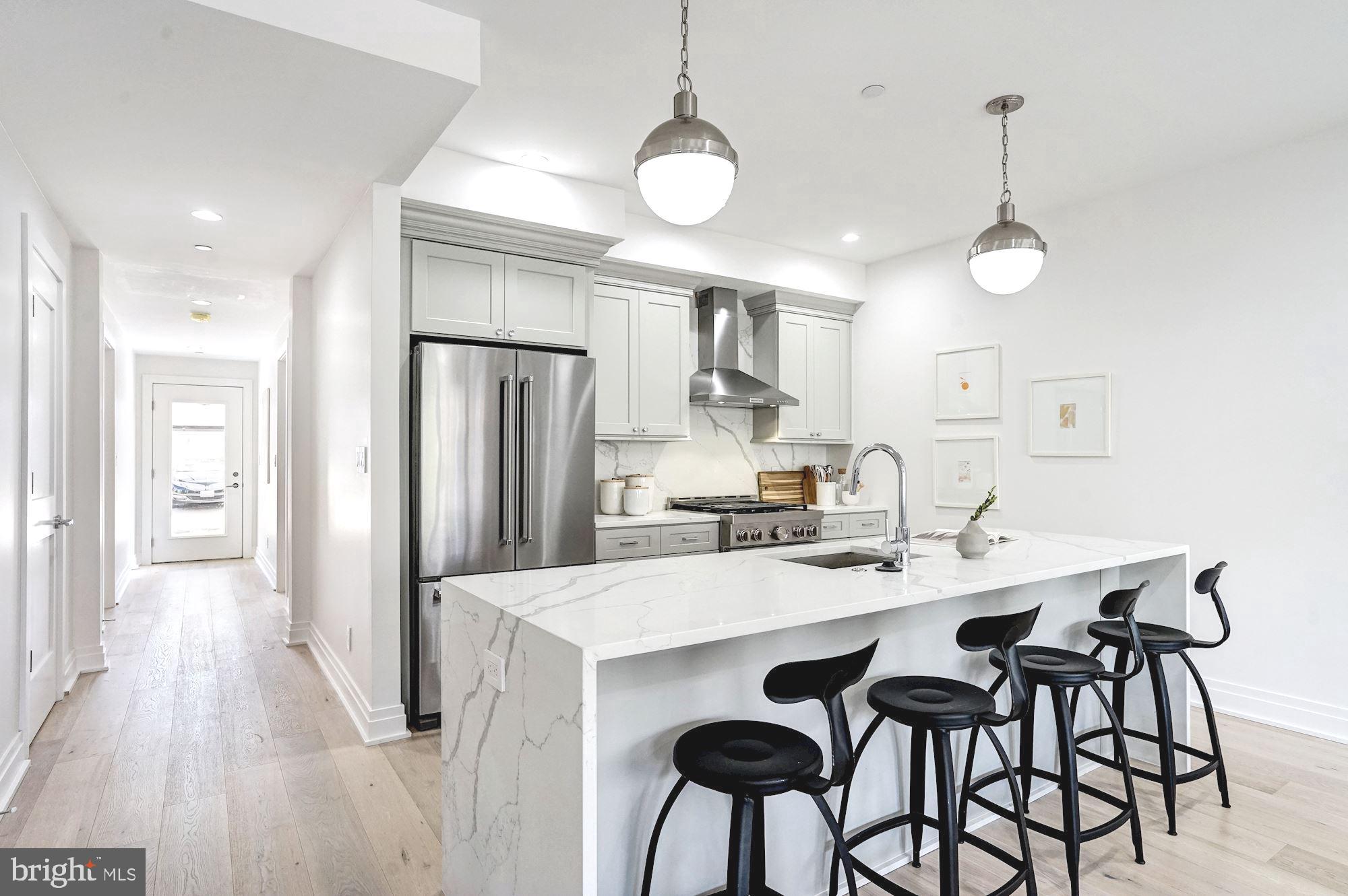 1603 Isherwood Street Northeast, Unit 2 Washington, DC 20002 - Photo 8 of 24 a kitchen with stainless steel appliances kitchen island granite countertop a dining table chairs and white cabinets