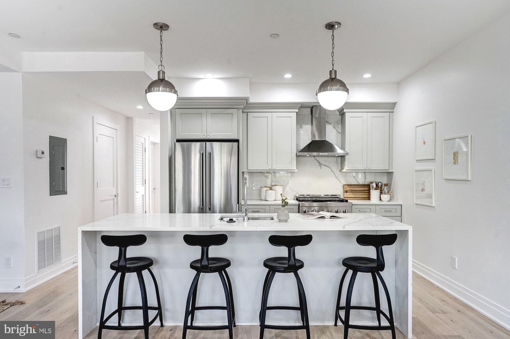 1603 Isherwood Street Northeast, Unit 2 Washington, DC 20002 - Photo 9 of 24 a kitchen with stainless steel appliances a table chairs and white cabinets