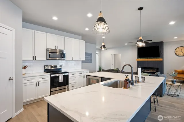 a kitchen with stainless steel appliances kitchen island granite countertop a sink a stove and a wooden floors