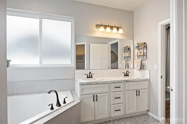 a bathroom with a double vanity sink mirror and bathtub