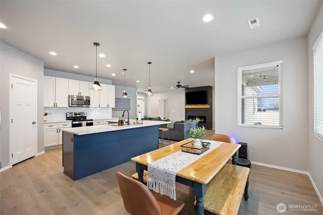 a kitchen with kitchen island a stove a sink a refrigerator and a dining table