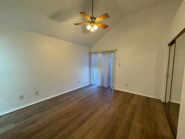 an empty room with wooden floor and a ceiling fan