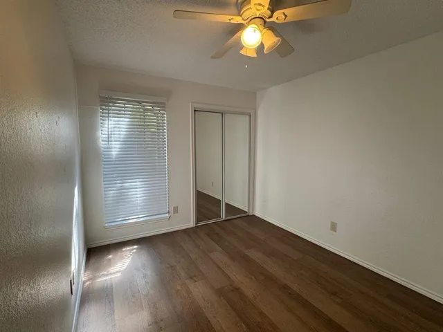 an empty room with wooden floor fan and windows