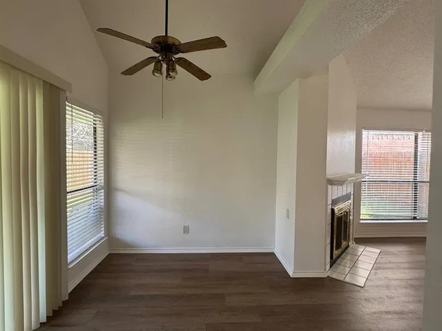 an empty room with wooden floor fan and windows
