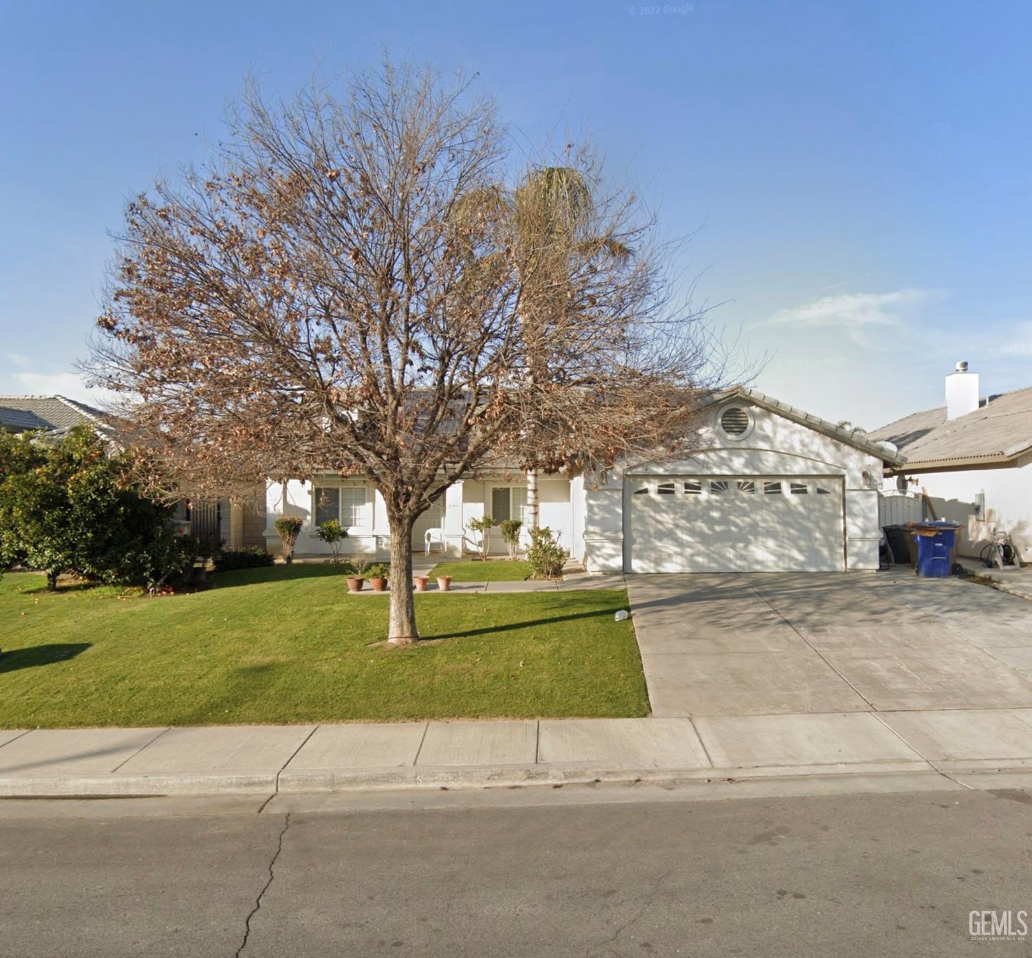 a view of a white house next to a yard with big trees