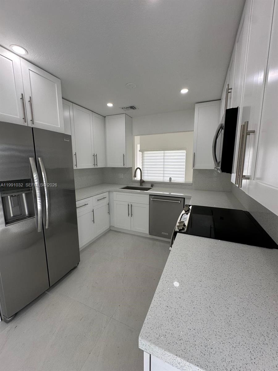 20926 Southwest 124th Ave Road Miami, FL 33177 - Photo 2 of 10 a kitchen with stainless steel appliances granite countertop a refrigerator a sink a stove and white cabinets
