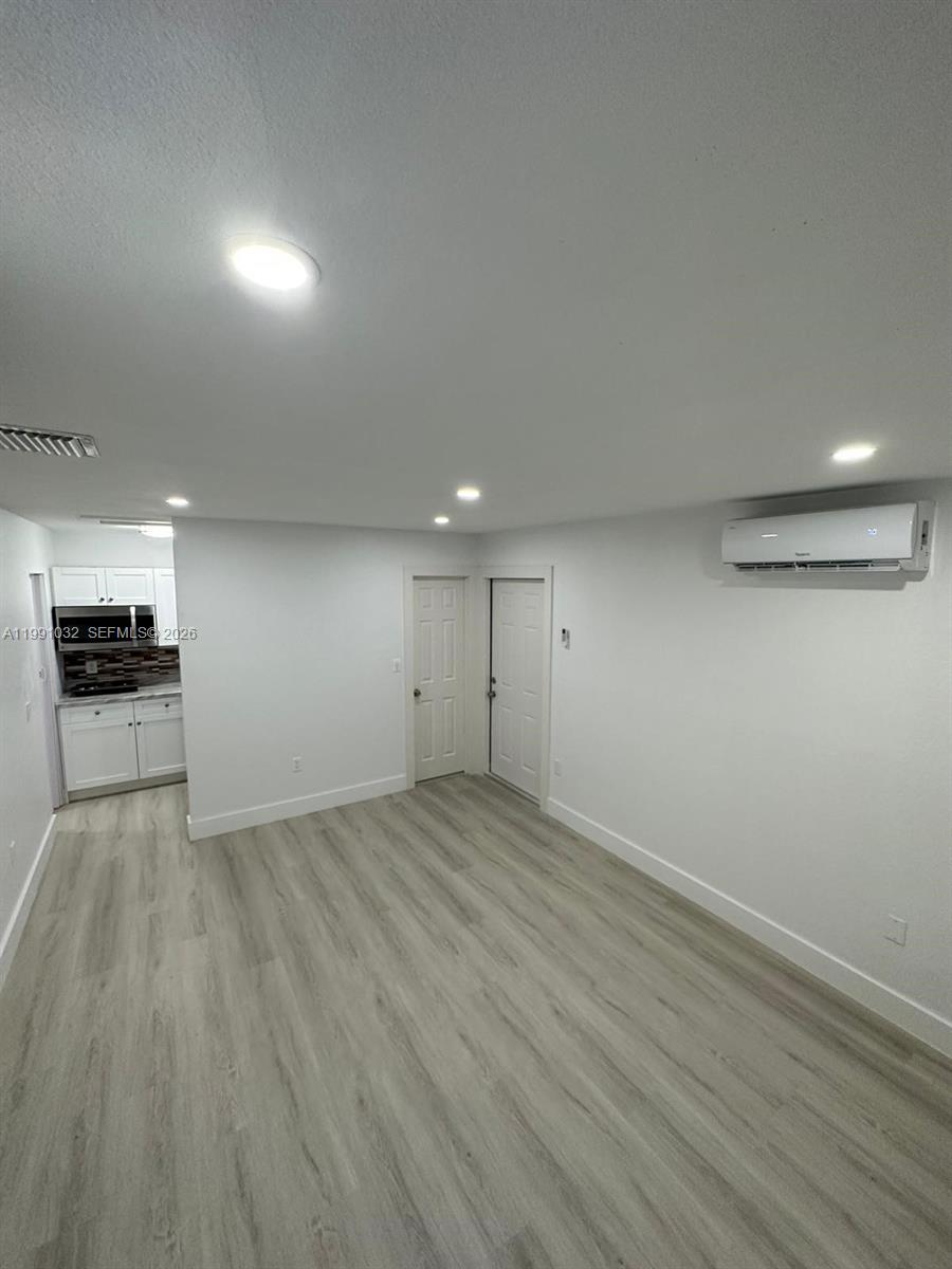 20926 Southwest 124th Ave Road Miami, FL 33177 - Photo 9 of 10 an empty room with wooden floor wooden cabinet and windows