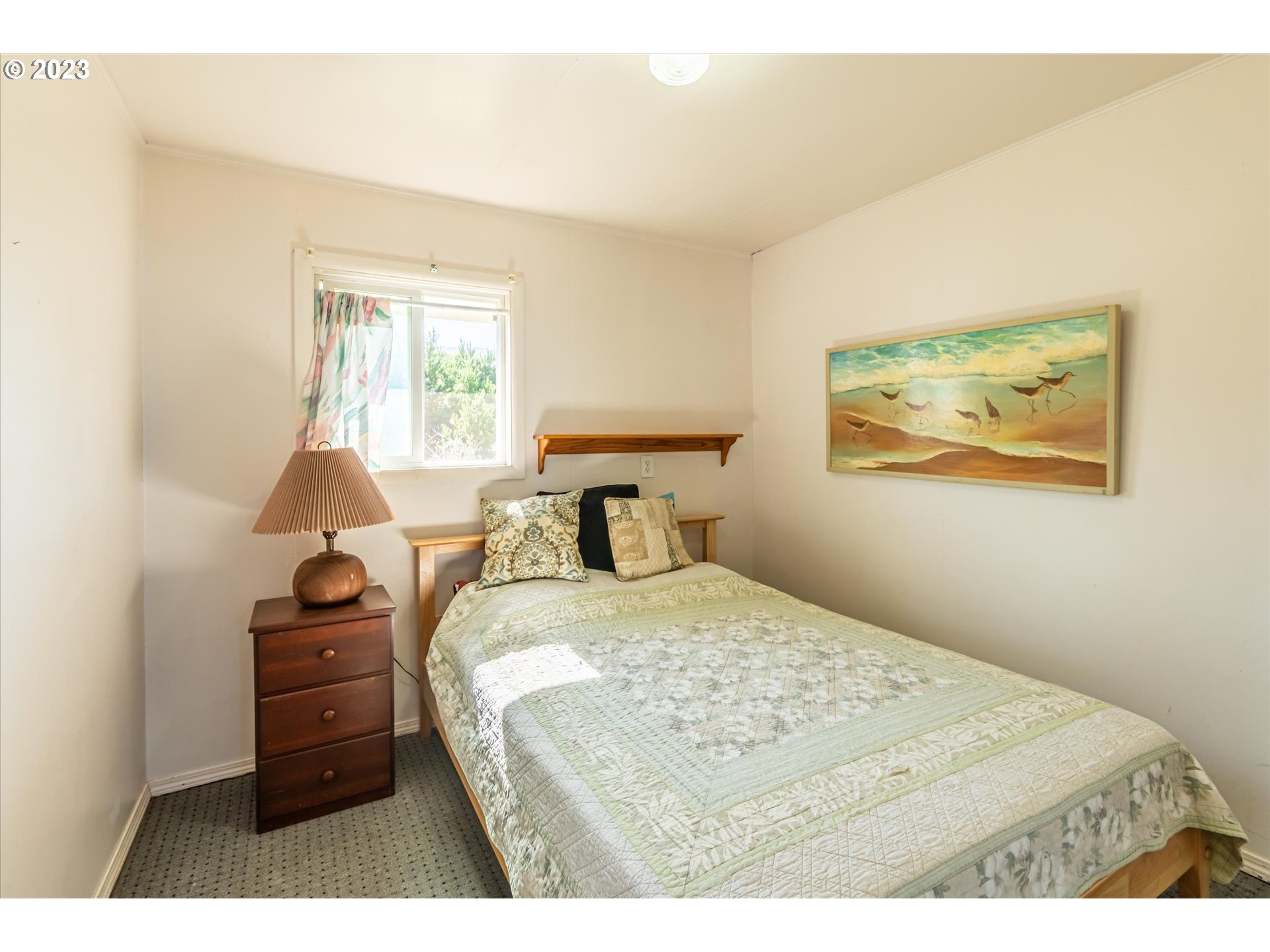 33032 Nesika Road Gold Beach, OR 97444 - Photo 10 of 35 a bedroom with a bed and a lamp on the dresser