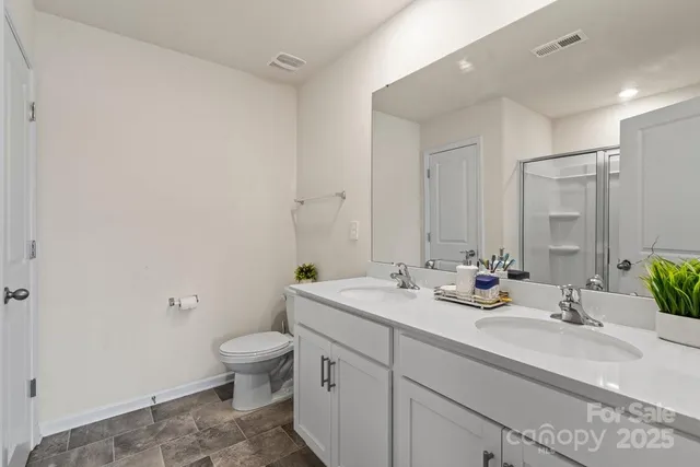 a bathroom with a double vanity sink toilet and a mirror