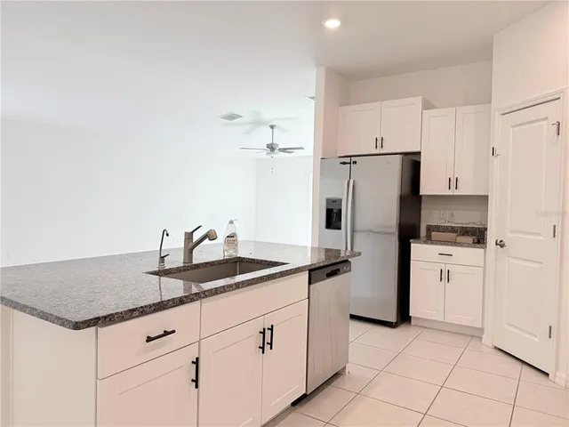 a kitchen with granite countertop a sink stainless steel appliances and white cabinets