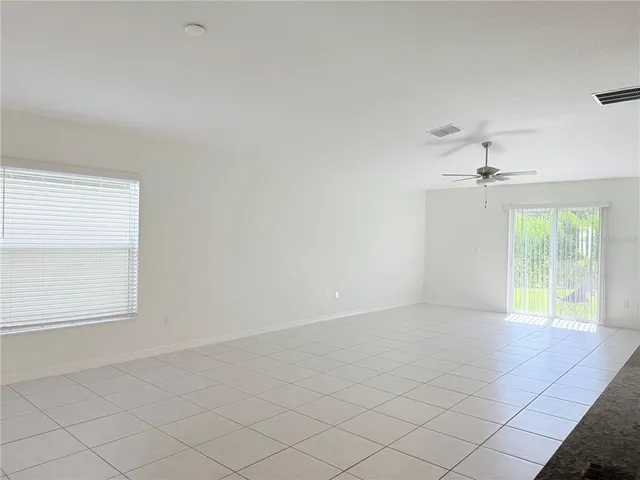 an empty room with windows and a ceiling fan