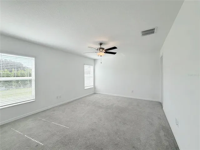 an empty room with windows and fan