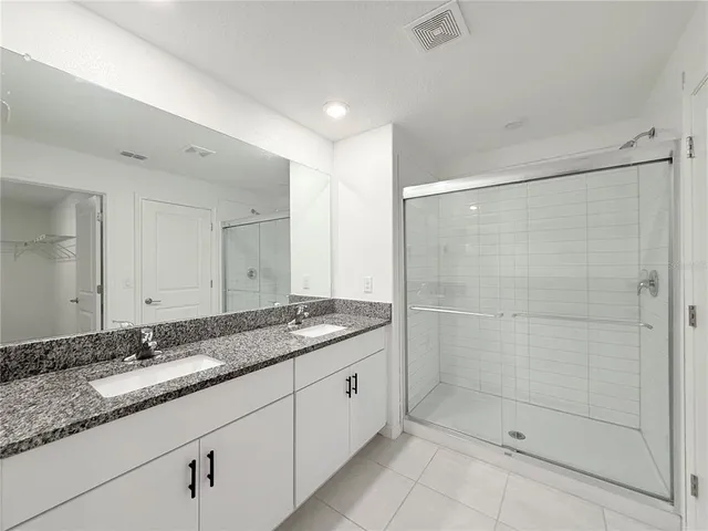 a bathroom with a granite countertop sink mirror and shower