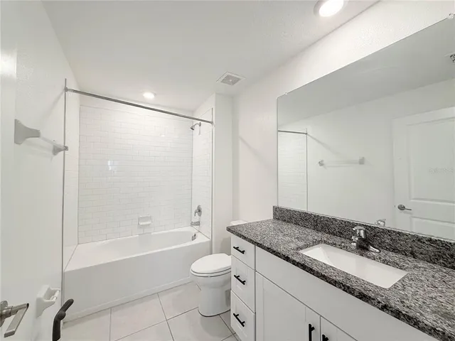 a bathroom with a granite countertop sink a toilet and shower
