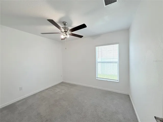 an empty room with a window and a fan
