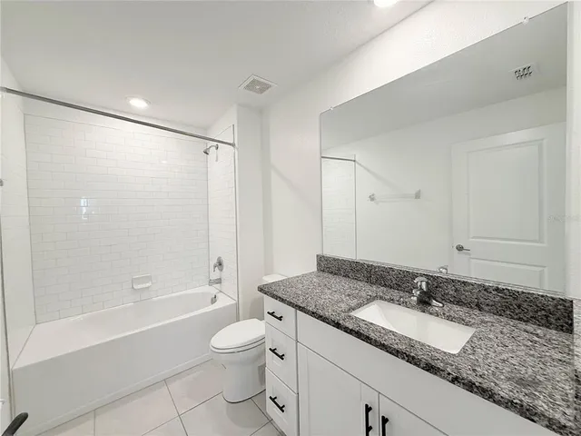 a bathroom with a granite countertop sink a toilet and shower