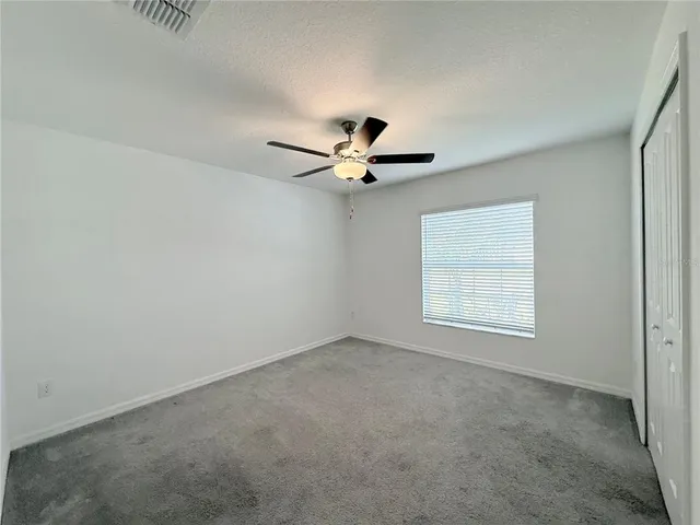 an empty room with a ceiling fan and window