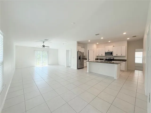 a large white kitchen with kitchen island granite countertop a stove a sink a refrigerator and white cabinets
