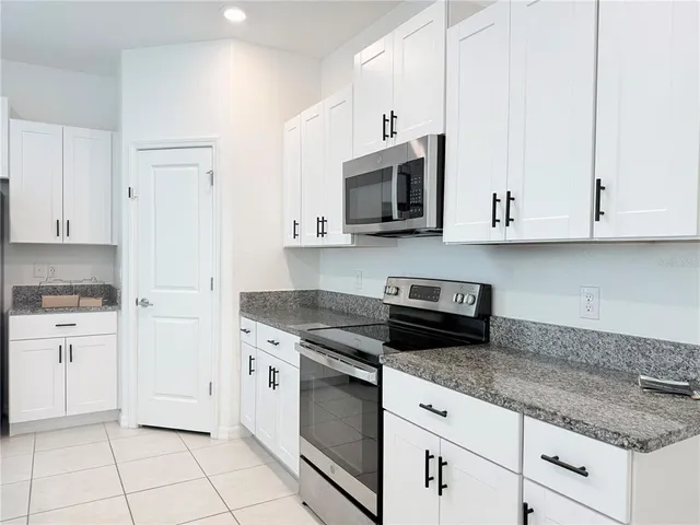 a kitchen with granite countertop white cabinets and white appliances