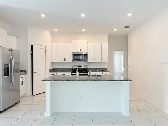 a kitchen with stainless steel appliances granite countertop a refrigerator and a stove