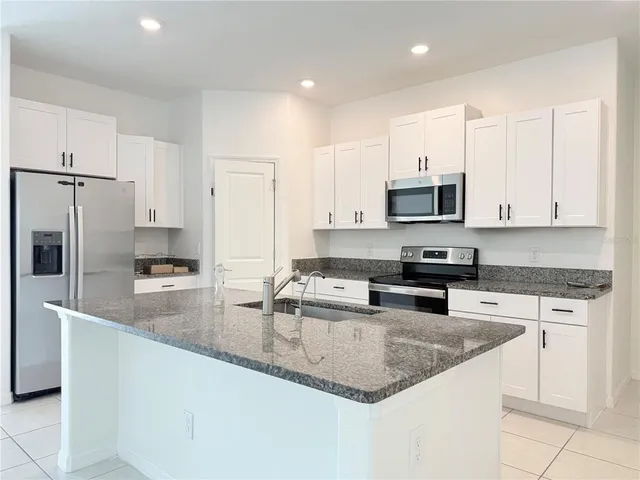 a kitchen with stainless steel appliances granite countertop a sink a stove a refrigerator a microwave and cabinets