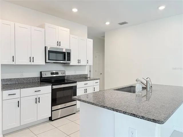 a kitchen with granite countertop a sink and white cabinets