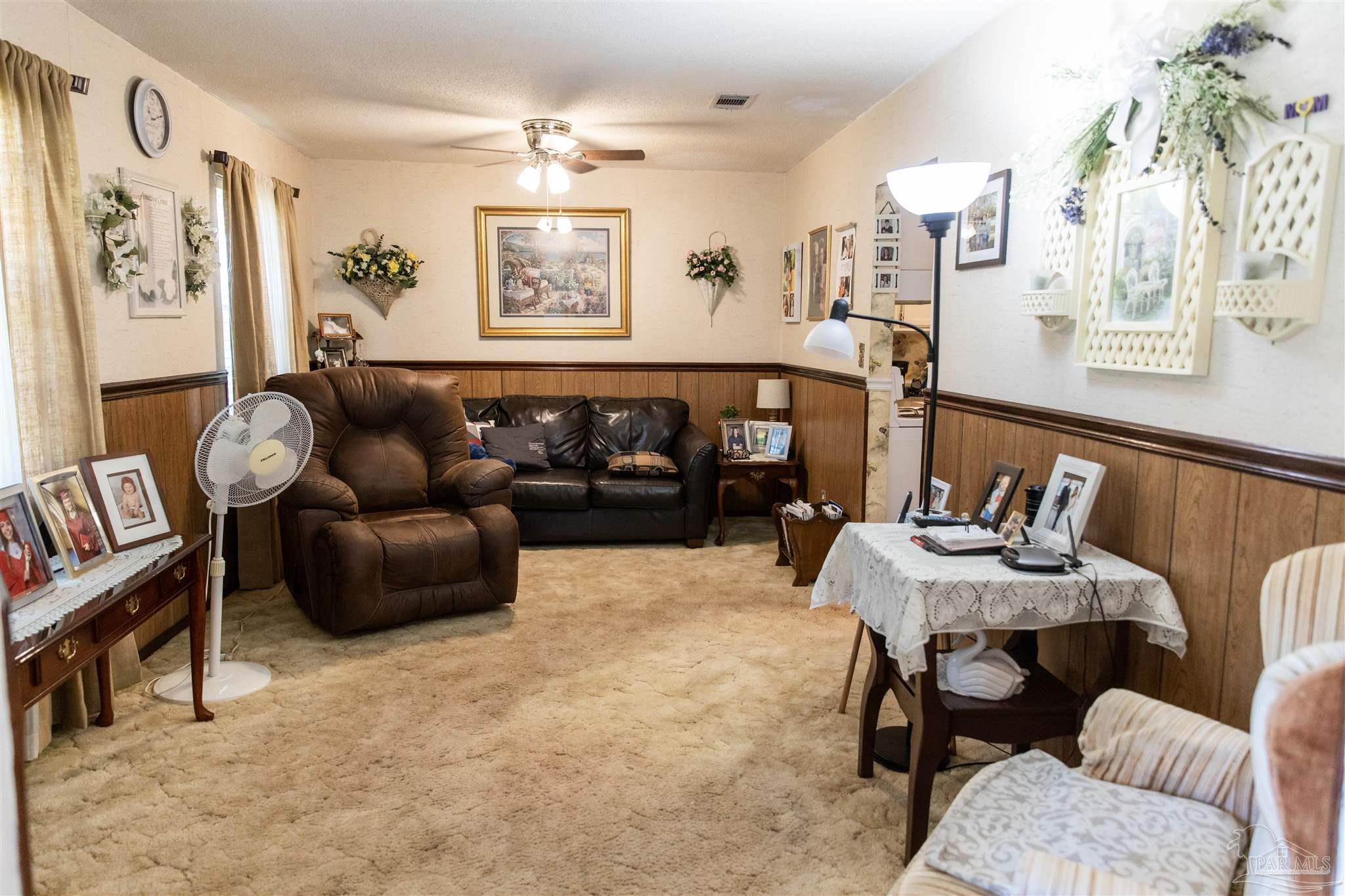 7569 Pine Meadows Loop Milton, FL 32571 - Photo 9 of 25 a living room with furniture and paintings on the wall