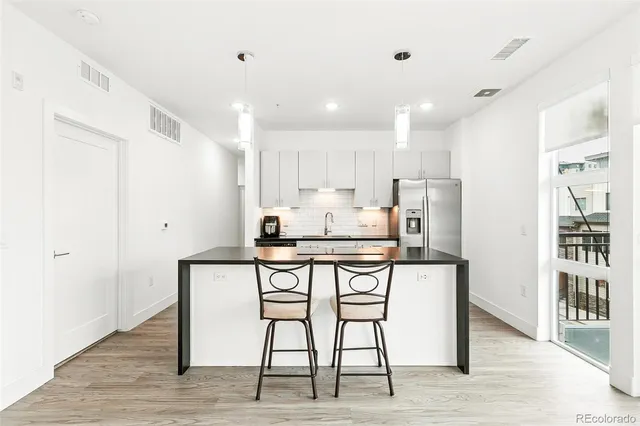 a kitchen with stainless steel appliances kitchen island granite countertop a dining table chairs refrigerator and sink