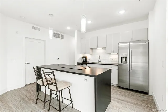 a kitchen with stainless steel appliances granite countertop a sink a stove a refrigerator and island with wooden floor