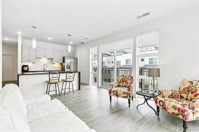 a living room with furniture and kitchen view with wooden floor