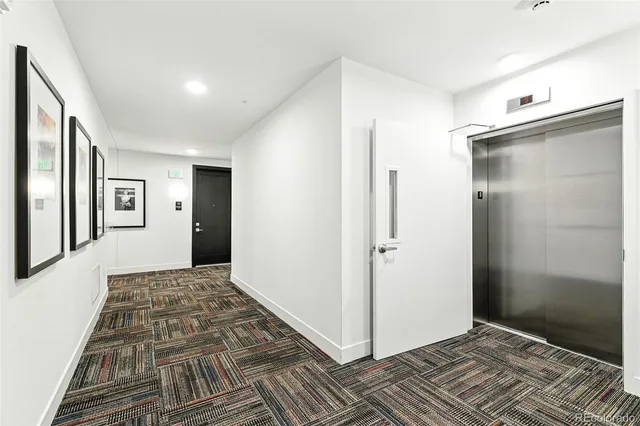 a view of a hallway with wooden floor and a bathroom