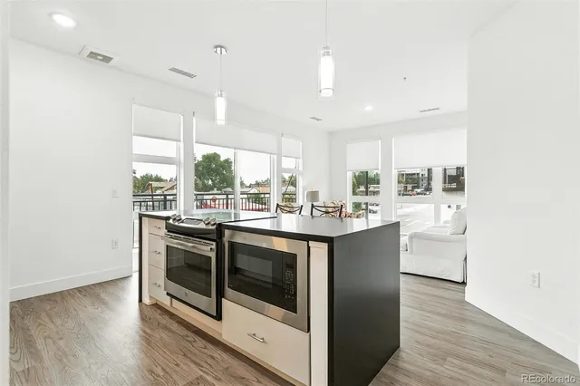 a kitchen with stainless steel appliances granite countertop a stove a sink and white cabinets with wooden floors