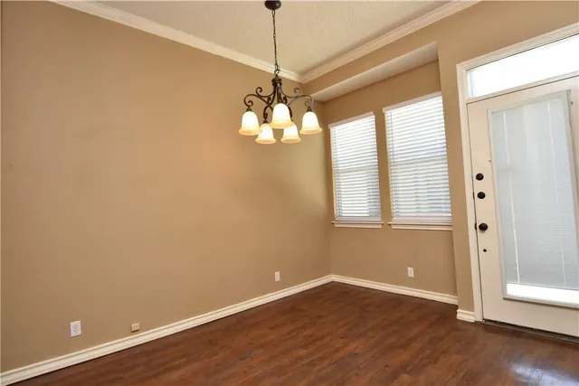 a view of a hallway with wooden floor and a kitchen