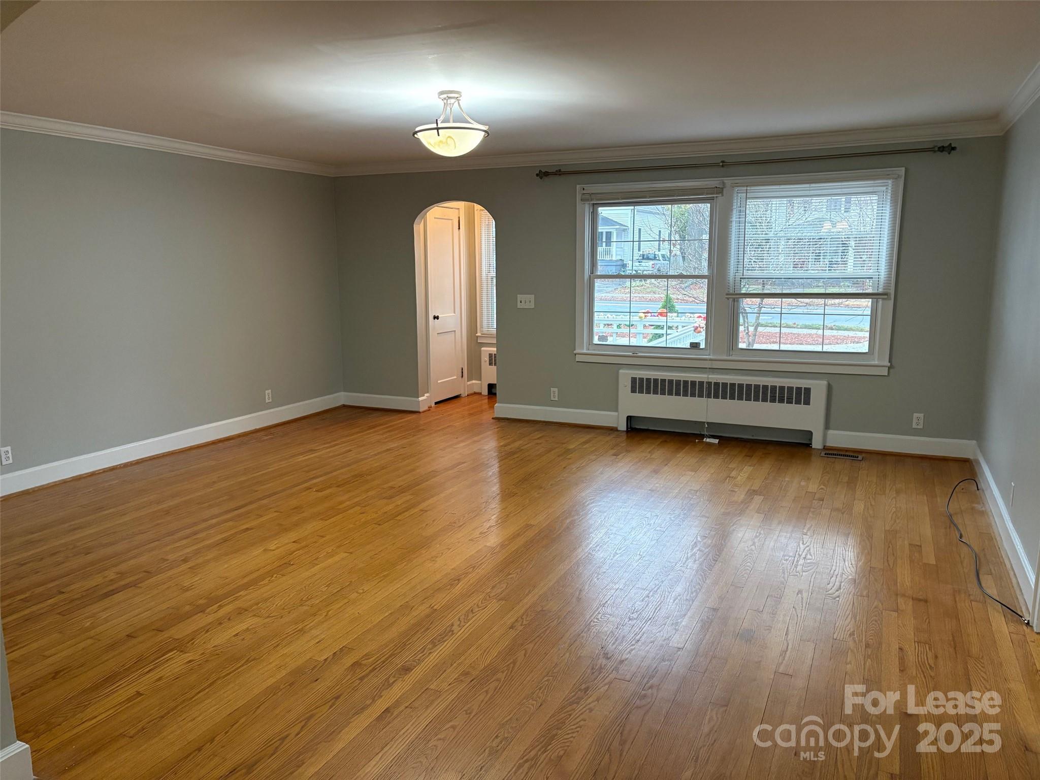 808 West Franklin Street Monroe, NC 28112 - Photo 3 of 9 an empty room with wooden floor and windows