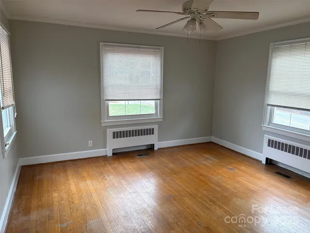 an empty room with a window and wooden floor