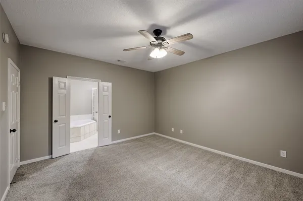 a view of an empty room and chandelier fan