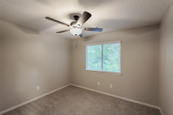 an empty room with a window and a fan