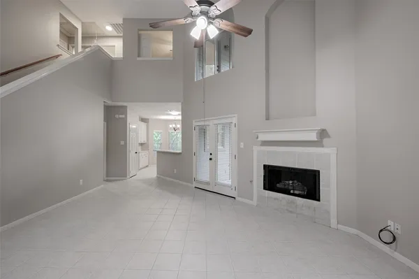 a view of an empty room with chandelier fan and fire place