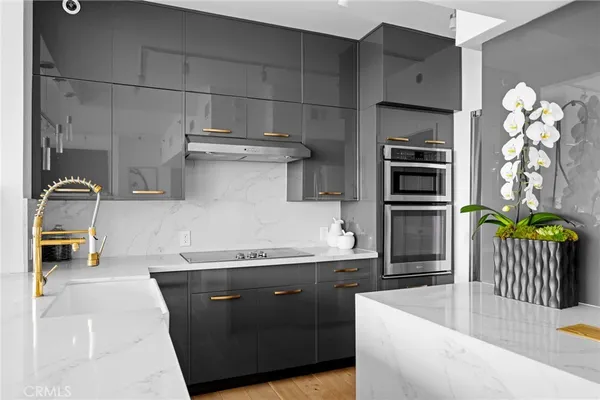 a kitchen with stainless steel appliances a sink and wooden floor