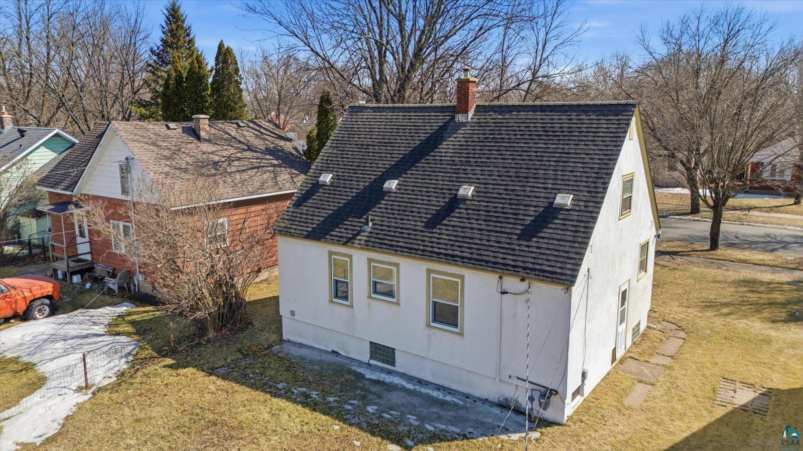 709 Michigan Street Hibbing, MN 55746 - Photo 29 of 47 View of side of home featuring roof with shingles, a chimney, and a yard
