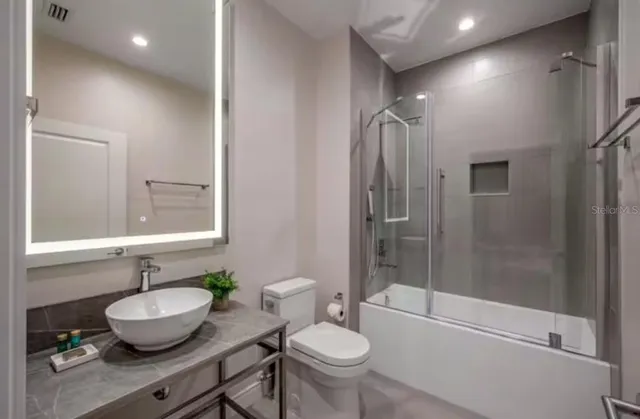 a bathroom with a granite countertop sink toilet a mirror and shower