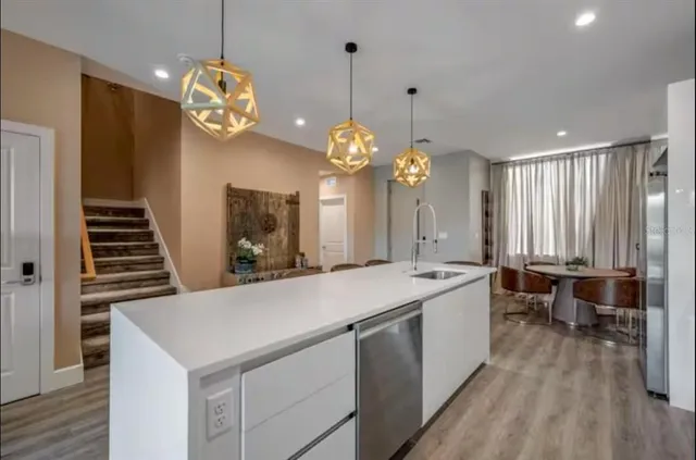 a large kitchen with kitchen island a stove a sink a refrigerator and a chandelier