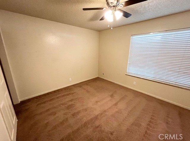 3056 Bedford Drive Merced, CA 95340 - Photo 12 of 19 an empty room with a chandelier fan and windows