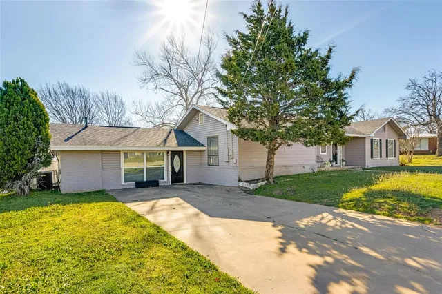 a front view of a house with a garden and trees