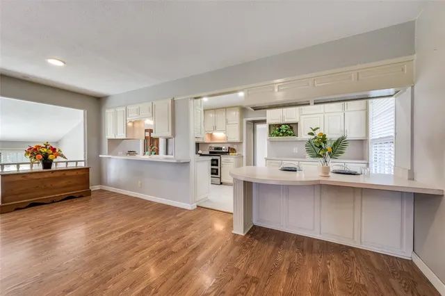 a living room with stainless steel appliances kitchen island granite countertop a sink dishwasher and a stove with wooden floor