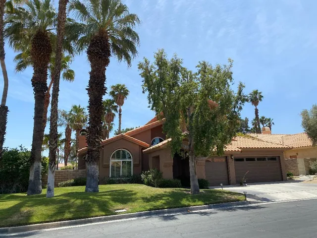 a front view of a house with a garden and tree