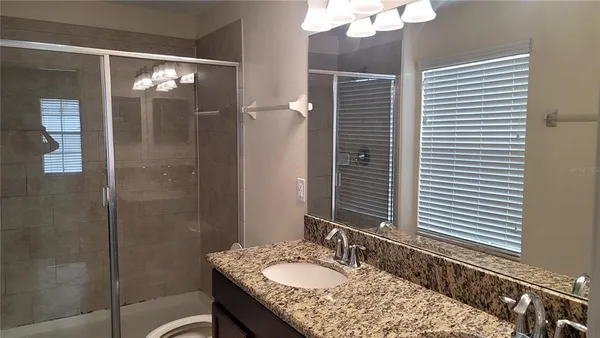 a bathroom with a granite countertop sink a shower and a mirror