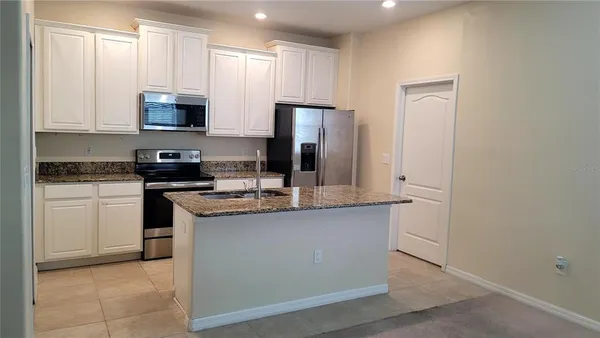 a kitchen with stainless steel appliances granite countertop a stove a sink and a refrigerator