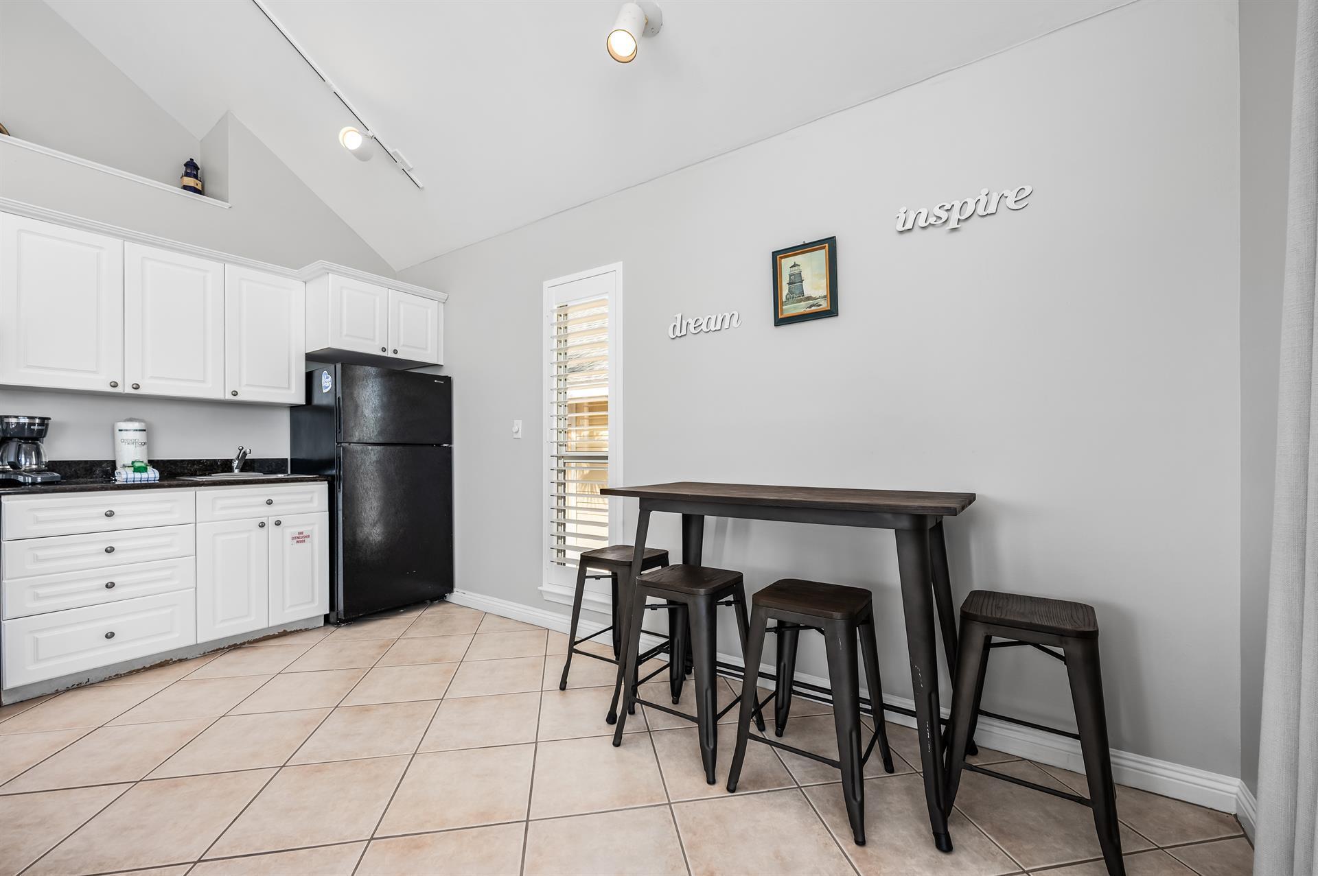 69 Crystal Beach Drive, Unit 8 Destin, FL 32541 - Photo 13 of 51 a kitchen with a table chairs refrigerator and cabinets